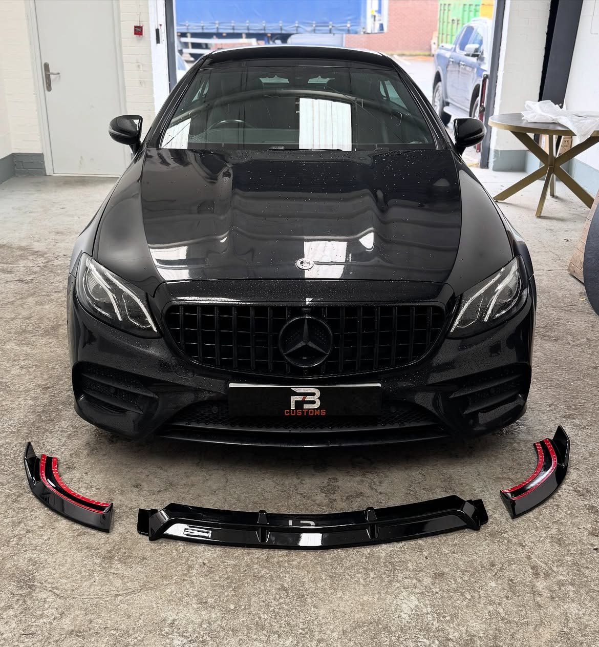 Black Mercedes with body kit components laid out in front