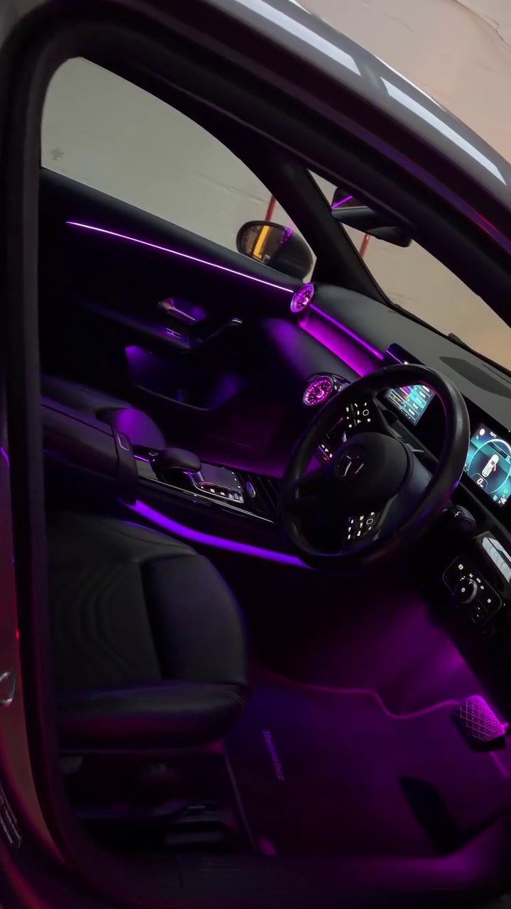 Purple ambient lighting across a vehicle dashboard, door and centre console