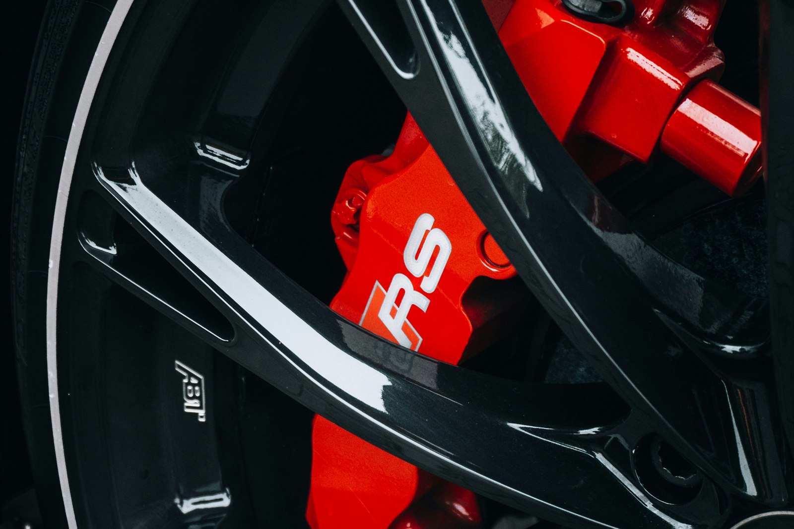 Close-up of a red brake caliper through wheel spokes