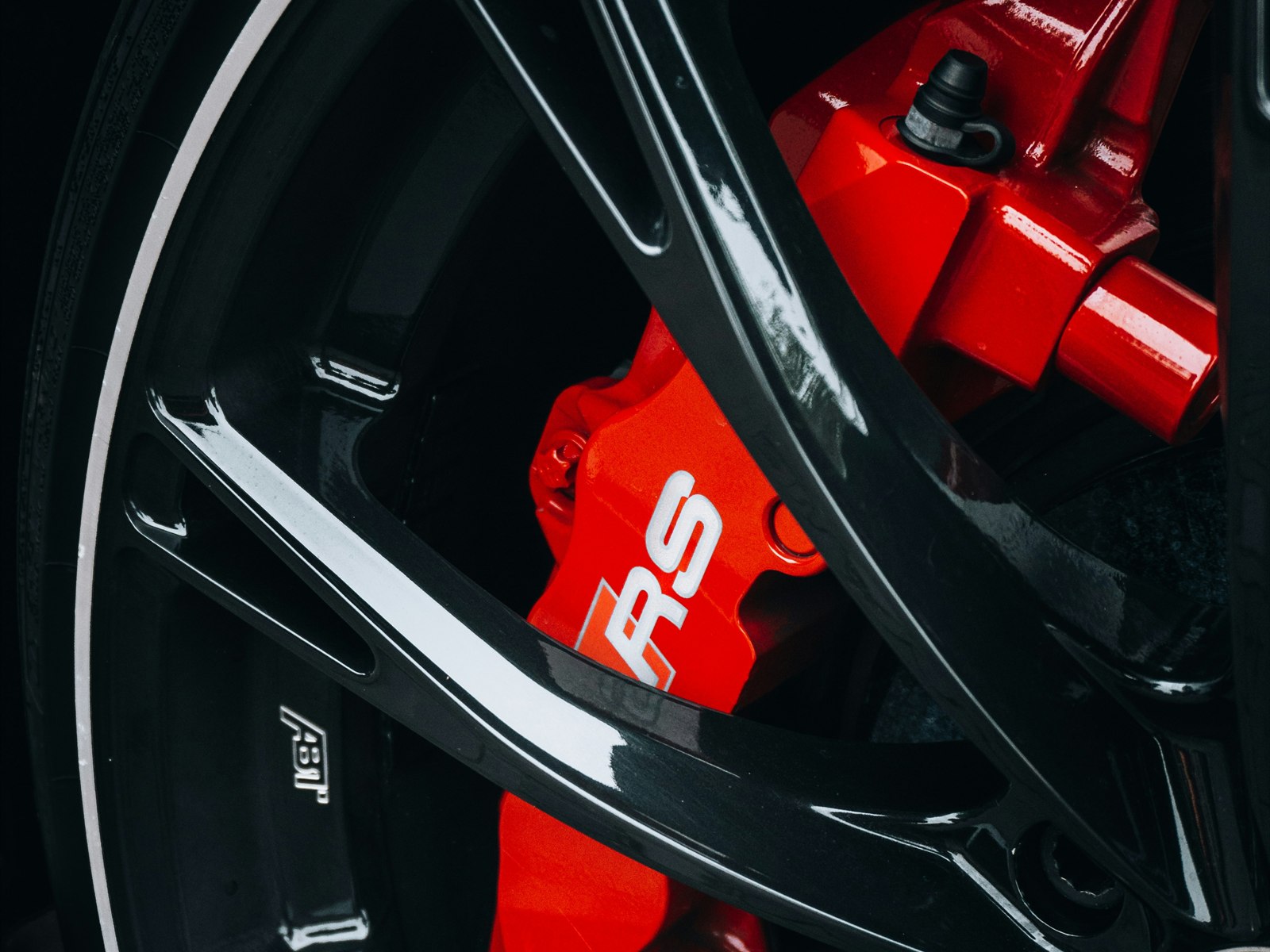 Red brake caliper behind a black alloy wheel